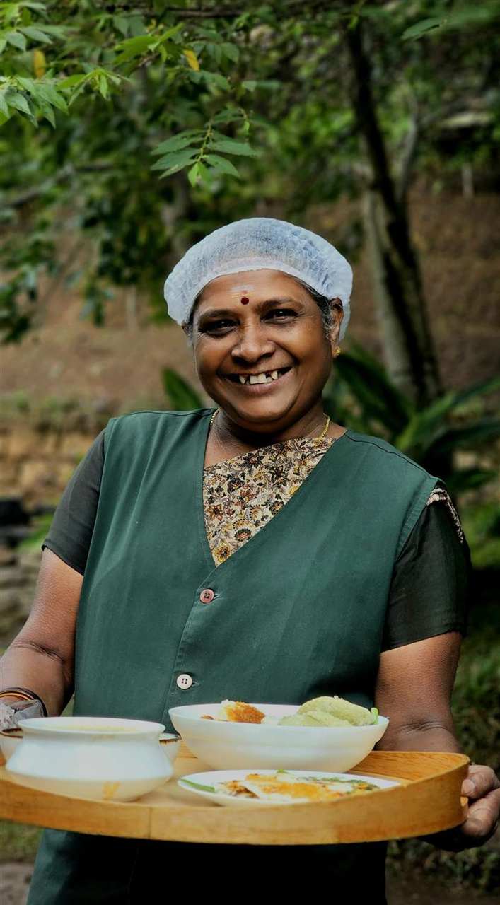 A smiling Kerala host serving a traditional breakfast