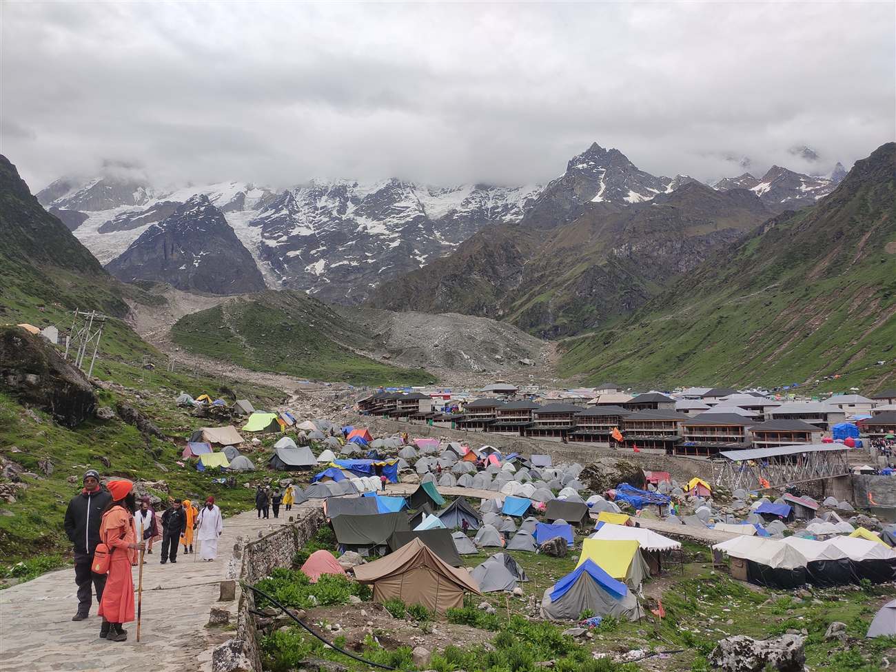 Tents and pilgrims in a Himalayan valley beneath snow-capped peaks