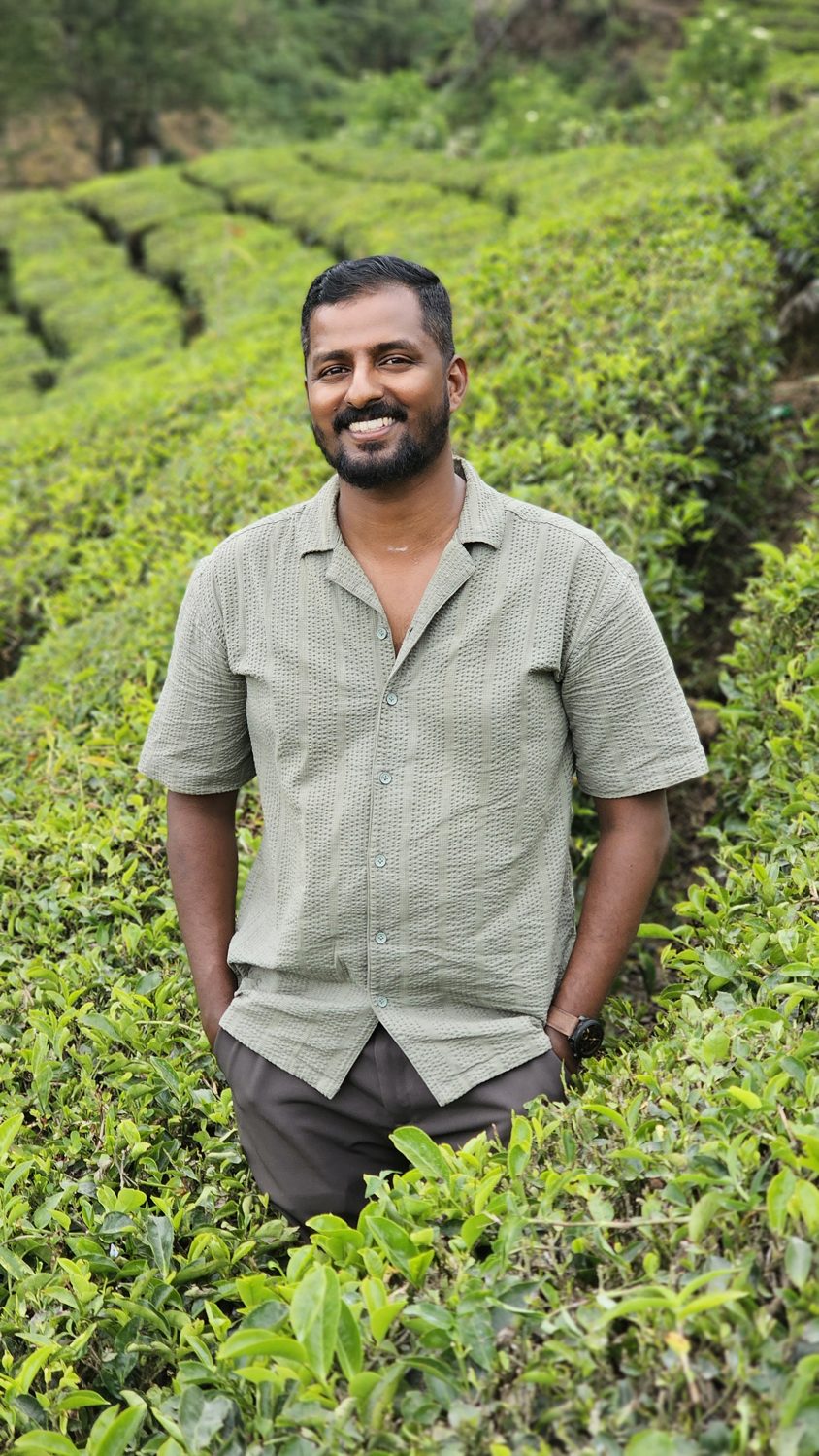 Abhijith, founder of Enroute Kerala, smiling among the tea bushes in Munnar