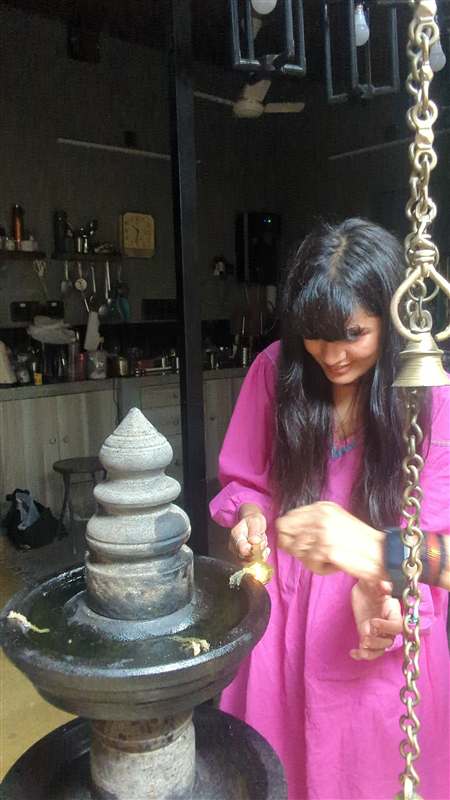 A woman lighting a traditional brass lamp